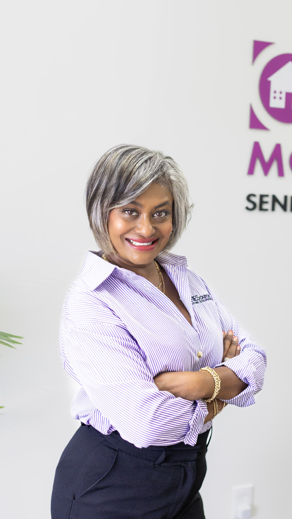 Sharon Natasha Sumere, co-owner of ONESource Moving Solutions Caledon, smiling in a striped company shirt with her arms crossed